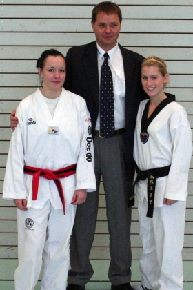 Jana Marie Thies (l.) freut sich mit Trainer Manfred Fechner (M.) und Kim Berthold (r.) über ihren 1. Dan.